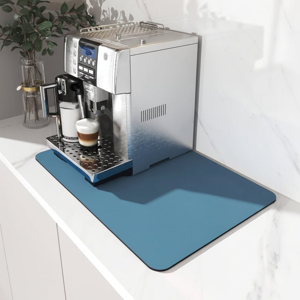 Solid blue rectangular mat with rounded corners under a silver espresso machine on a white marble counter 1