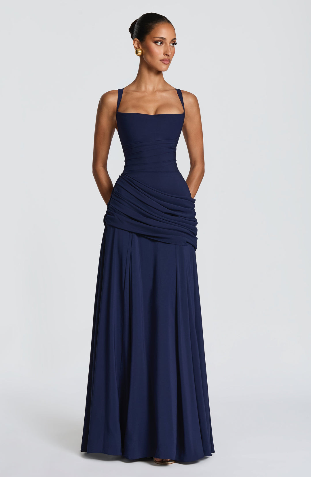 Navy blue maxi dress, front view with hands tucked into side pockets and the long skirt hanging full.