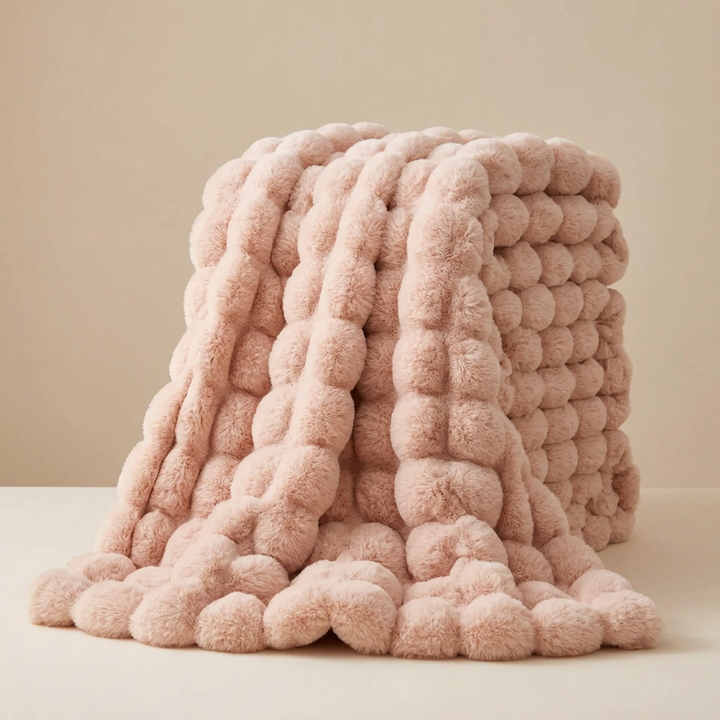 Pink pom-pom textured plush blanket folded in a stack with one end draped down 15