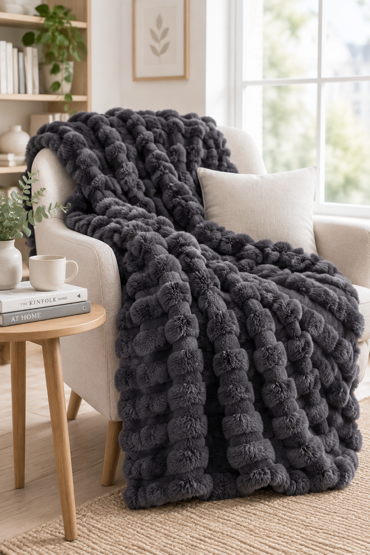 Dark charcoal plush bubble-textured throw draped over a cream armchair next to a wooden side table 14