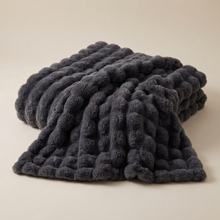 Dark gray bubble-textured plush blanket laid in soft folds on a neutral background 14
