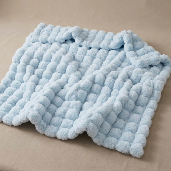 Light blue fluffy bubble-textured blanket laid out flat on a beige surface 17