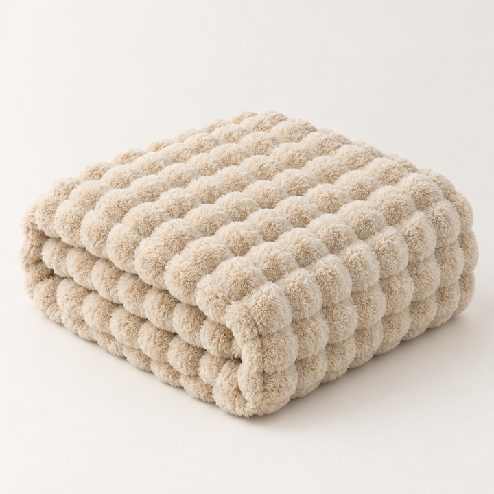 Beige bubble-textured plush blanket folded in a neat stack on a plain background 13