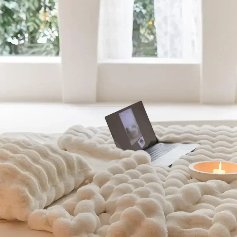 Cream faux fur throw with wavy ridged texture, with a laptop and lit candle in front of a window 8