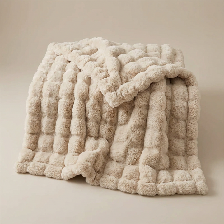Beige bubble-textured plush blanket folded loosely on a neutral background 13