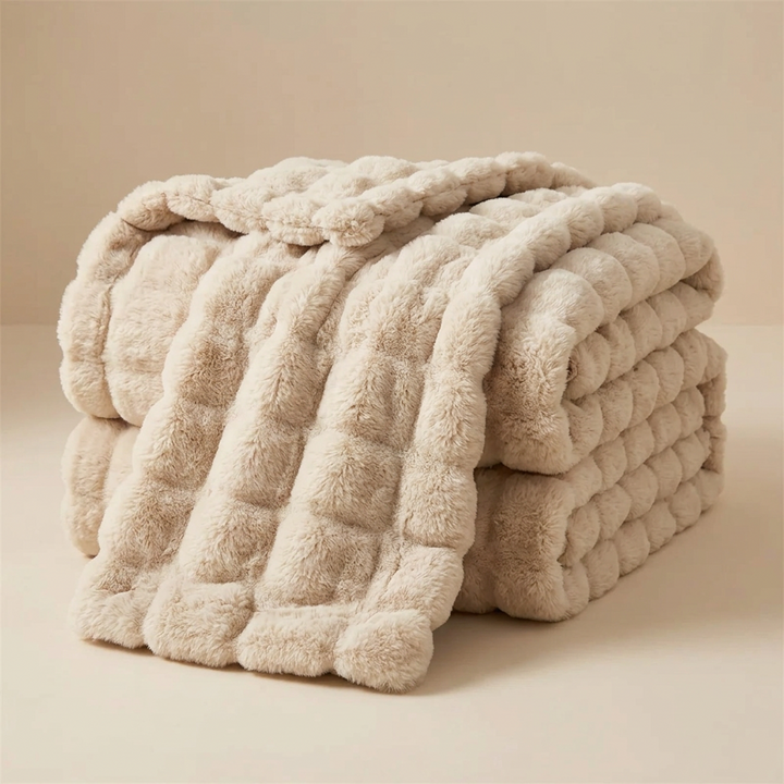 Beige bubble-textured plush blanket folded and draped over itself against a neutral background 13