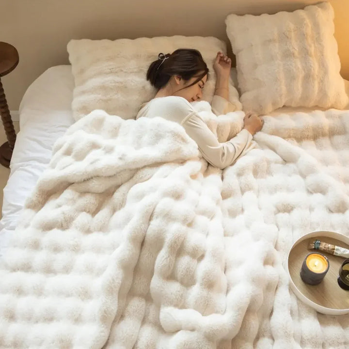 Woman sleeps on her side under a cream white fluffy blanket with candle tray nearby 5