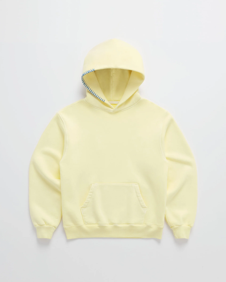 Pale yellow hoodie laid flat, front view, with blue stitching along the hood edge and a kangaroo pocket 1