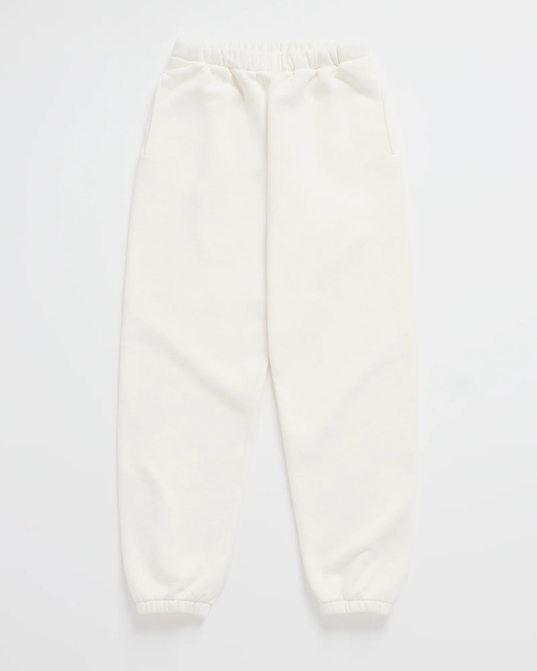 Cream white jogger sweatpants laid flat, with a gathered elastic waistband, side pockets and elastic ankle cuffs 7