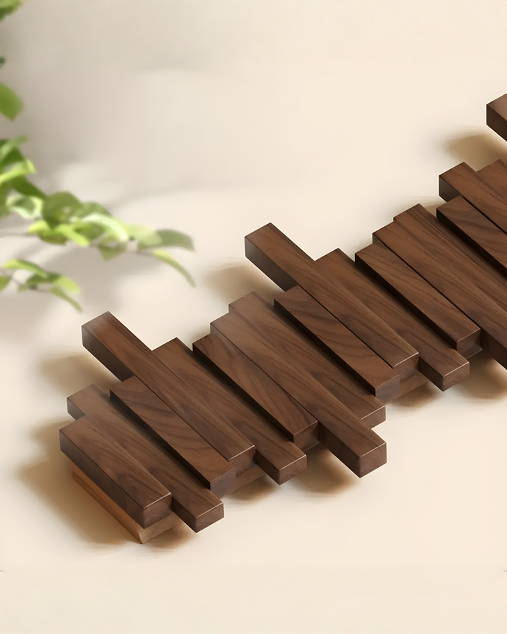 Dark wooden rack lying flat on a cream surface beside a leafy plant, showing the staggered bars from above at an angle.