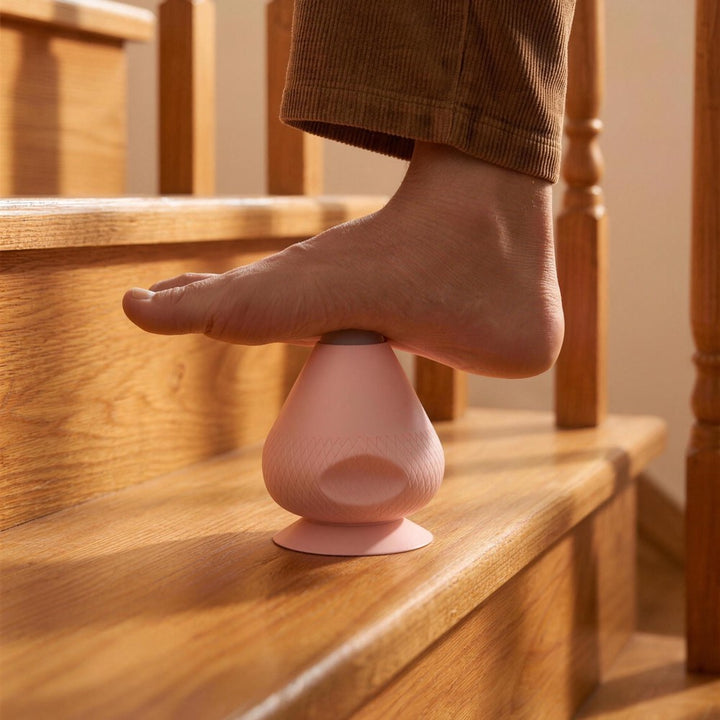 Bare foot rests on top of a pink massager standing on a wooden stair step, used as a foot massager. 8