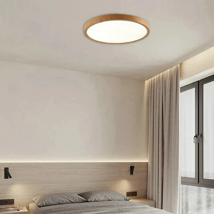 Light-wood round ceiling light in a minimalist bedroom with a low bed, wall reading lamps and tall curtains. 3