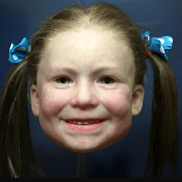 Smiling child-like girl mask with long brown pigtails tied with blue polka-dot bows