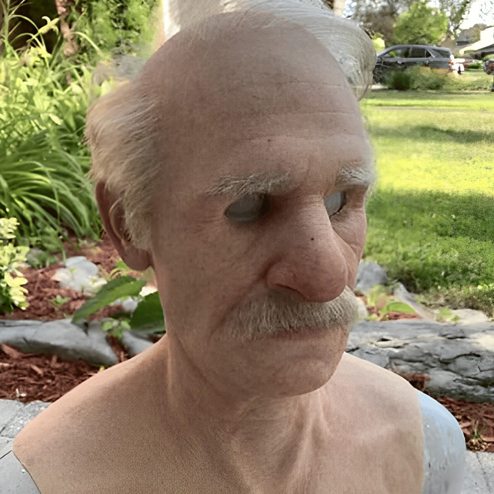 Elderly man mask with gray hair, bushy eyebrows and a mustache, shown outdoors in a garden with the shoulders and chest included. 21