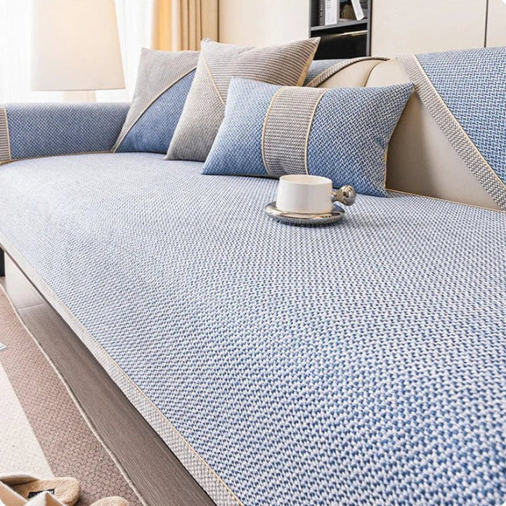 Couch cover in light blue woven fabric with a braided trim on a sofa, with blue and gray pillows. 11