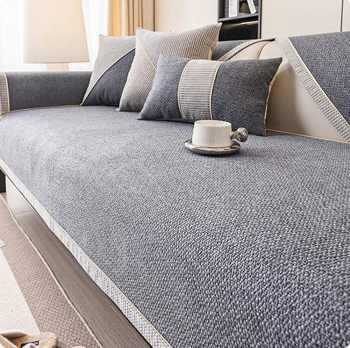 Couch cover in charcoal gray woven fabric with a braided trim on a sofa, with gray pillows and a white cup. 12