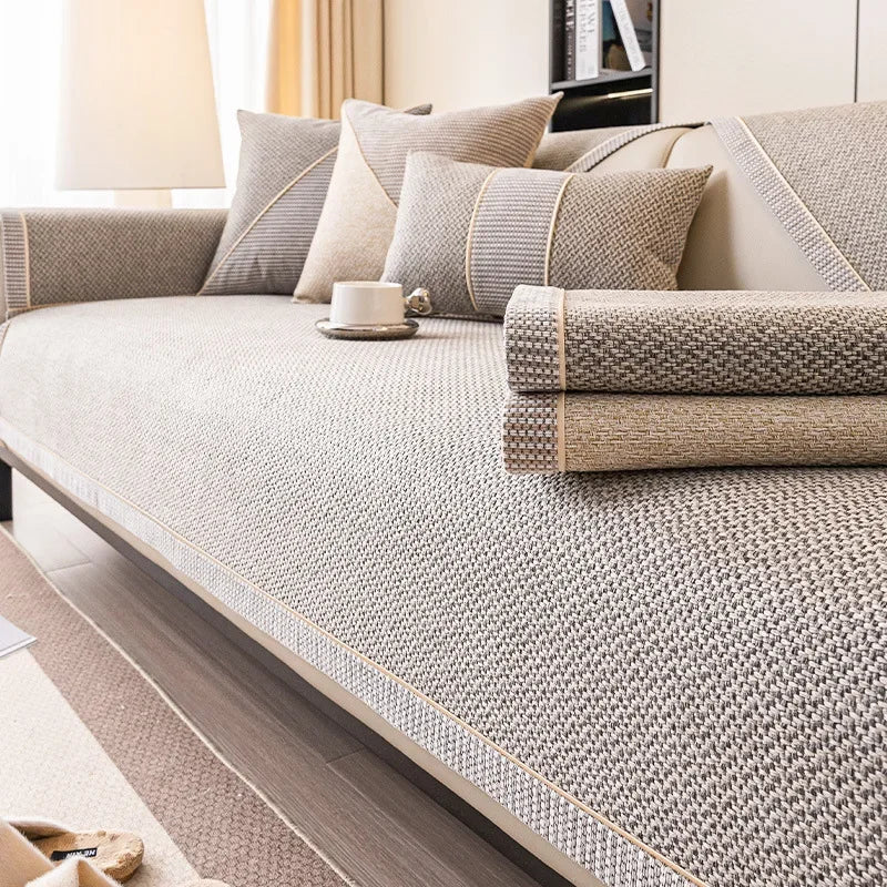 Two folded couch cover pieces, one gray and one tan, stacked on a sofa covered in gray woven fabric. 6
