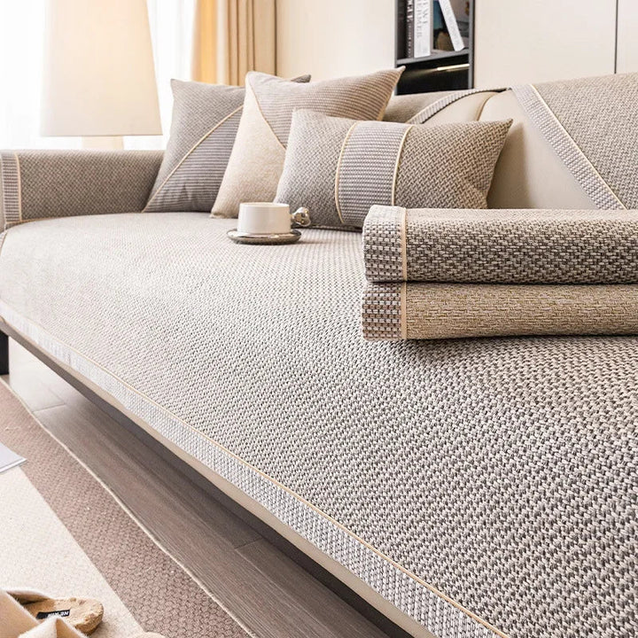 Two folded couch cover pieces, one gray and one tan, stacked on a sofa covered in gray woven fabric. 6