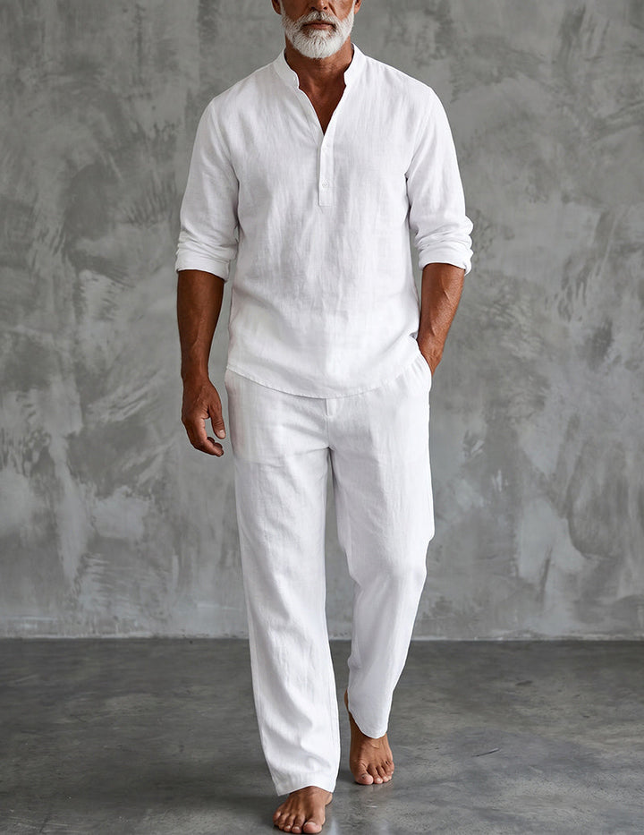 Men's white linen Henley shirt and relaxed pants set, front view against a gray textured wall.