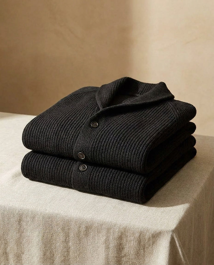 Two folded black cardigans stacked on a linen-draped table, showing the shawl collar and button placket 11
