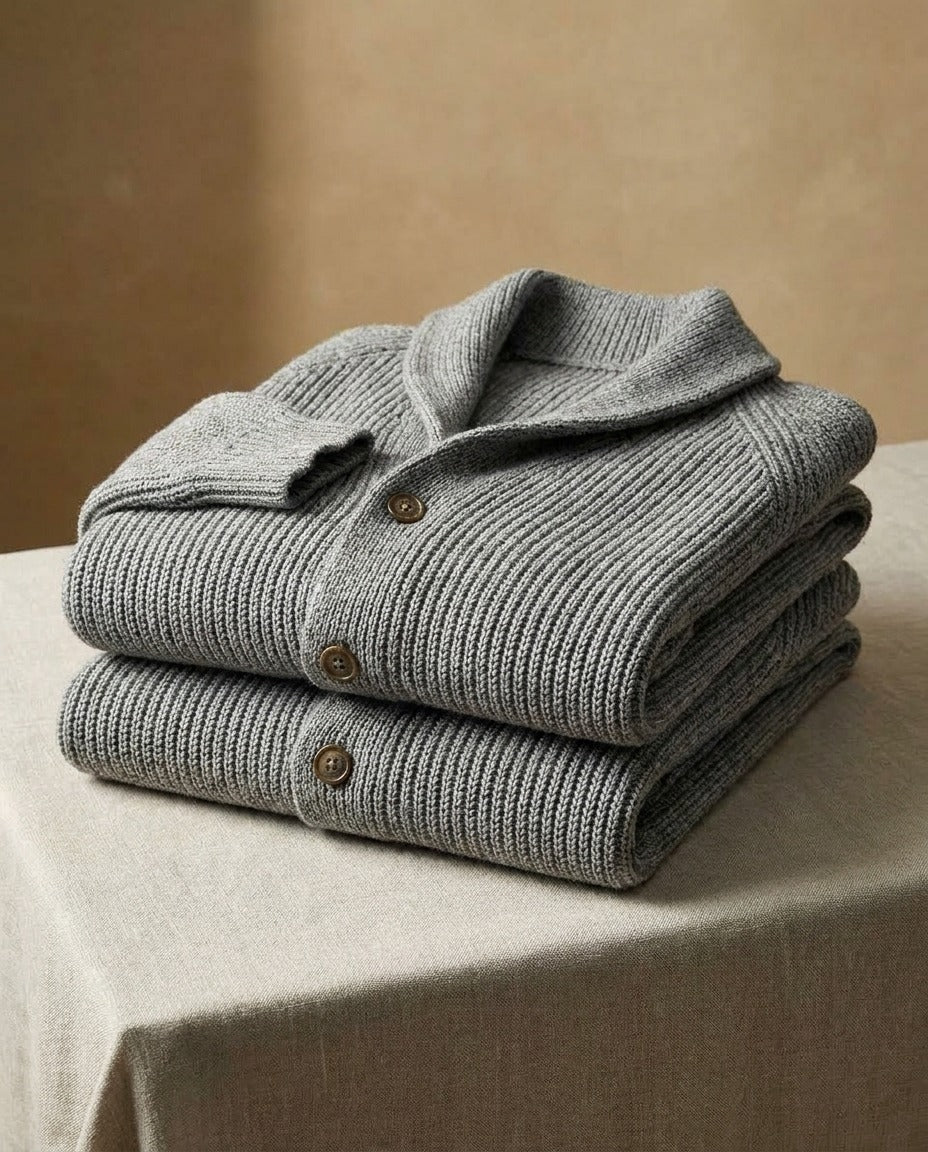 Two folded gray cardigans stacked on a linen-draped table, with tan buttons and a chunky rib knit 9
