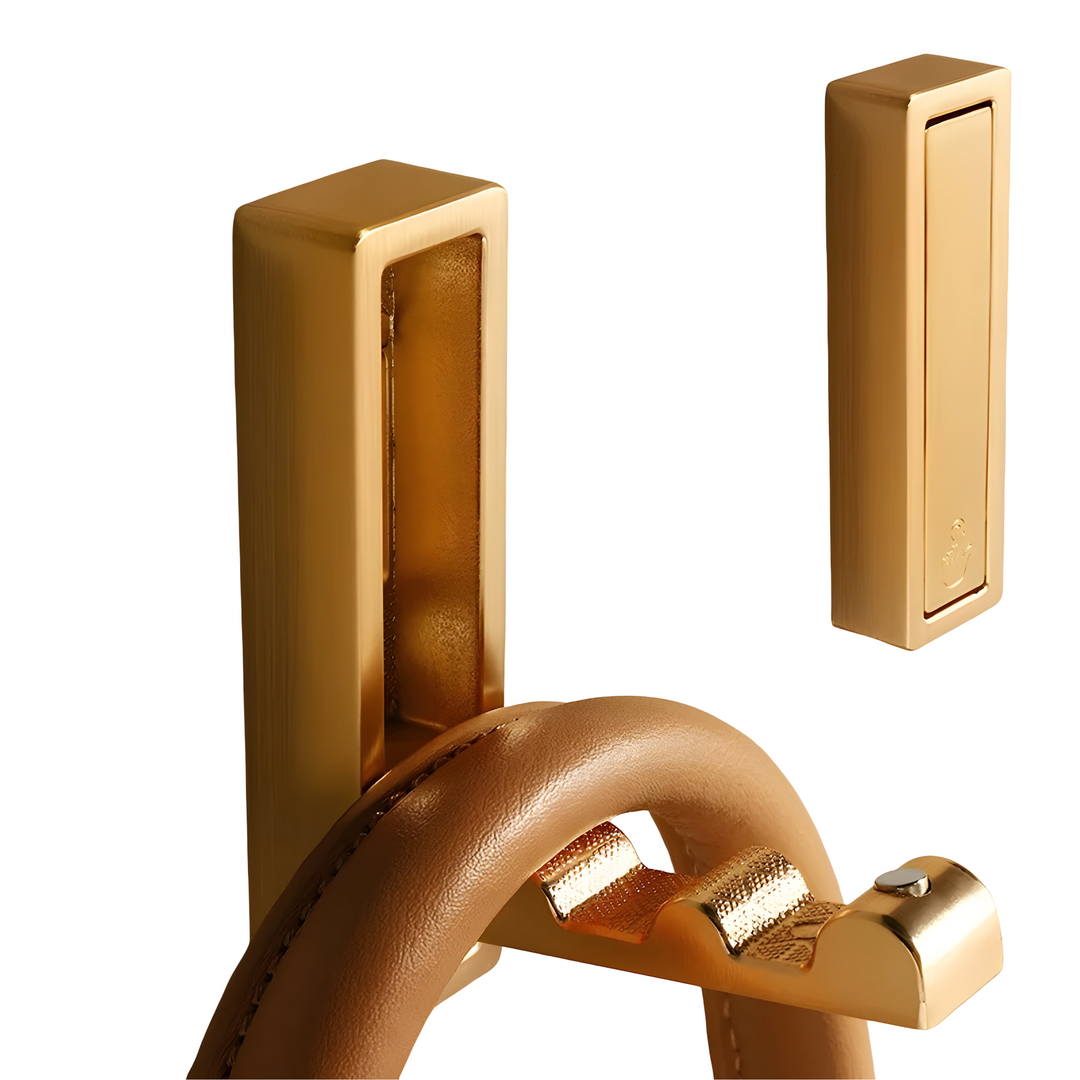 Hidden Wall Hooks in gold stainless steel, one folded out holding a tan leather bag handle.