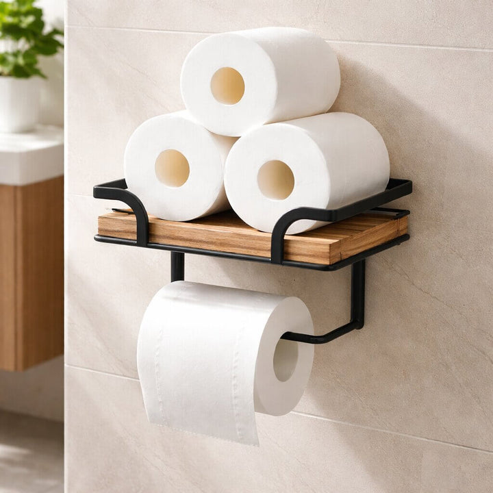 Toilet paper holder detail with three spare toilet paper rolls on the wooden shelf above a roll hanging below.