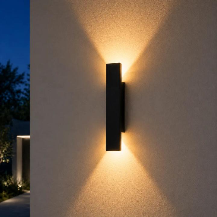 Black aluminium wall light on a stucco wall with warm up and down beams.