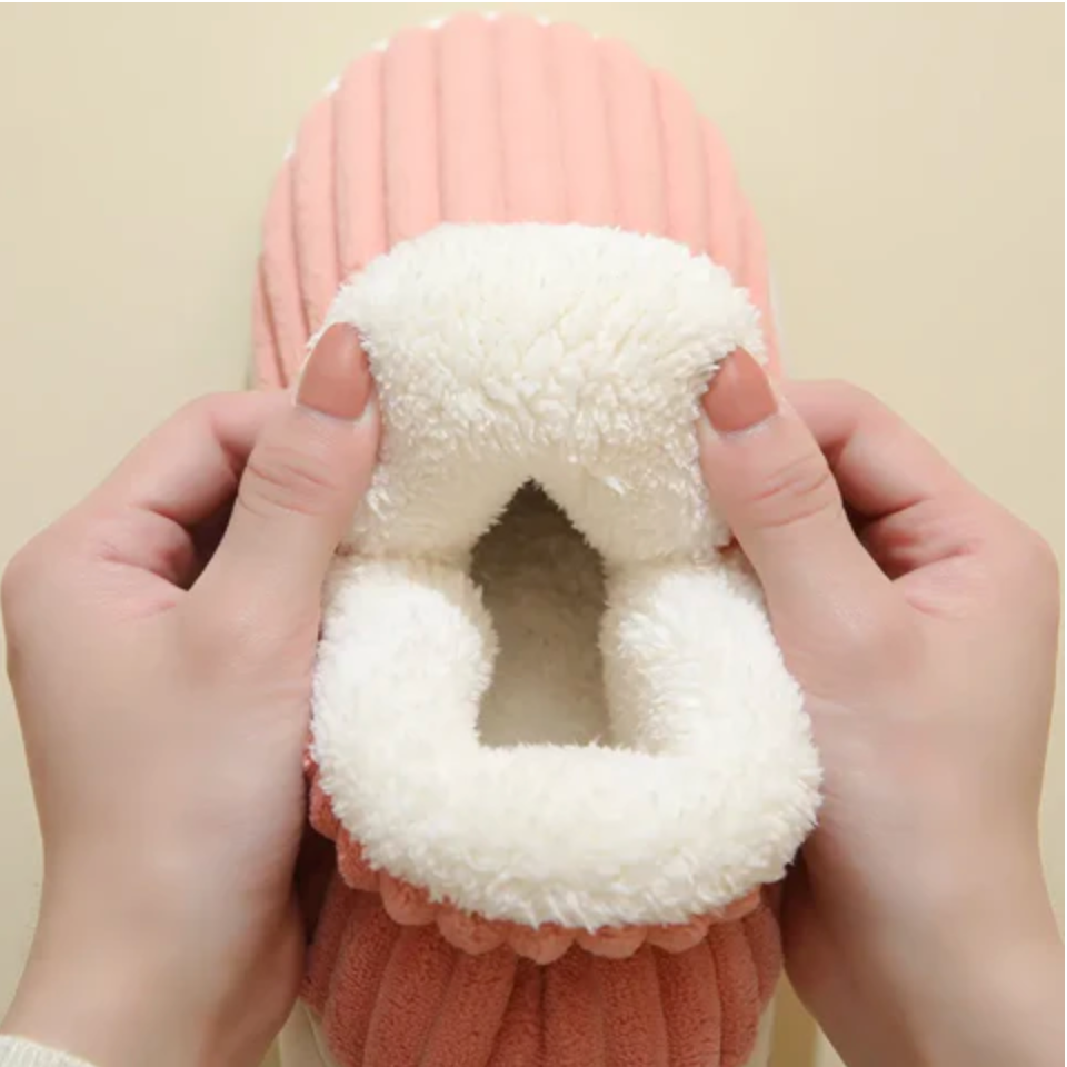 Detail of pink ribbed slipper stretched open to show the thick, soft white fleece lining inside.