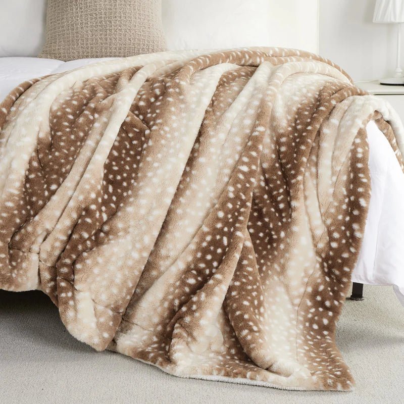 Spotted faux fur throw in brown and cream spread across the foot of a bed.