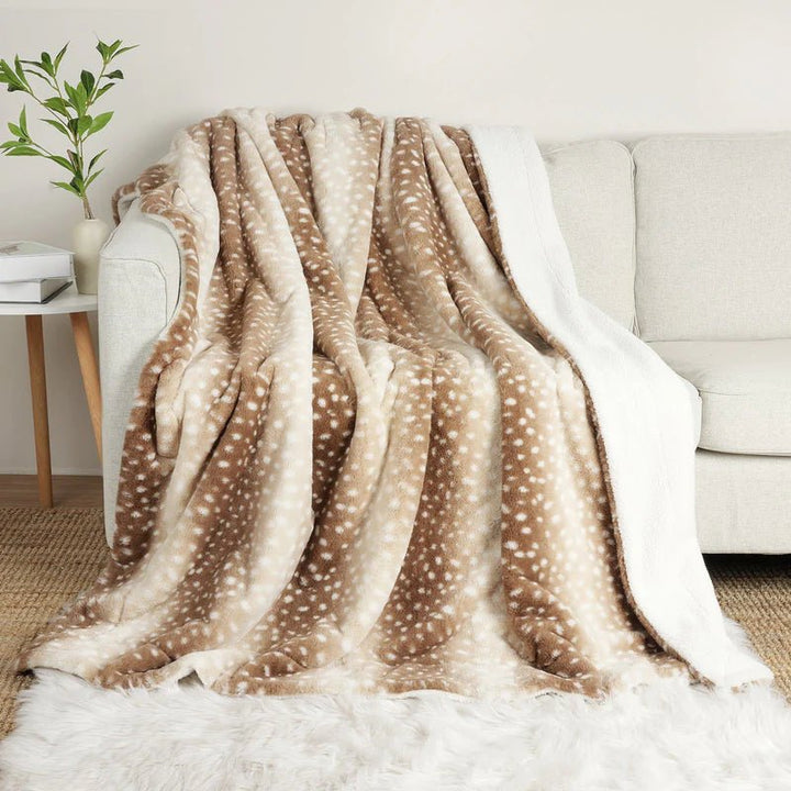 Brown and cream spotted faux fur throw draped over a light sofa, with the white sherpa side showing along the edge. 1