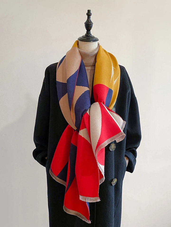 Red, mustard, navy and tan geometric scarf knotted loosely at the front of a mannequin wearing a black coat. 5