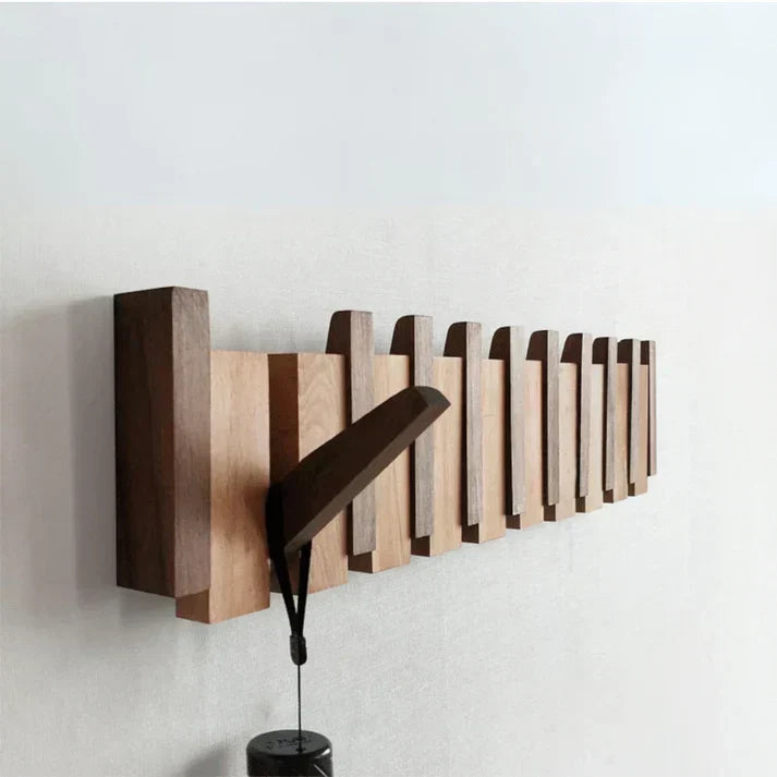 Angled close view of the wall rack with one hook folded out and a small item hanging from it 2