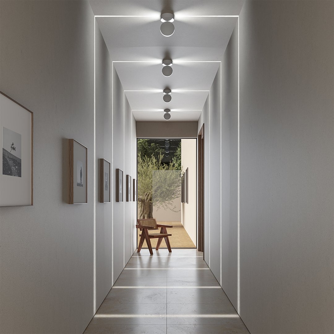 White LED wall sconce with a square beam effect on a wall in a hallway.