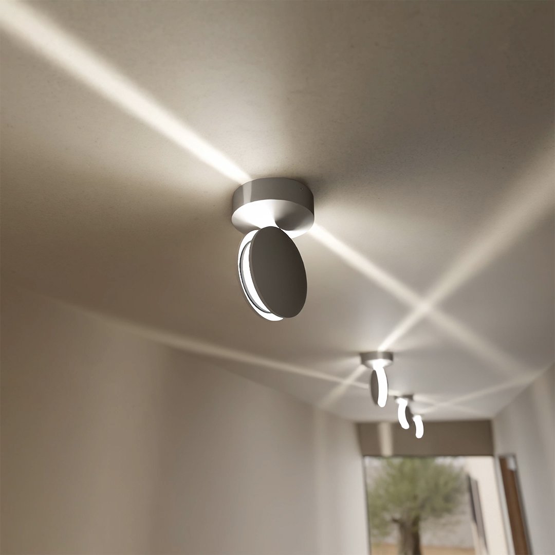 White LED wall sconce detail showing a rotating spotlight throwing diagonal beams overhead.