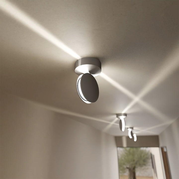 White LED wall sconce detail showing a rotating spotlight throwing diagonal beams overhead.