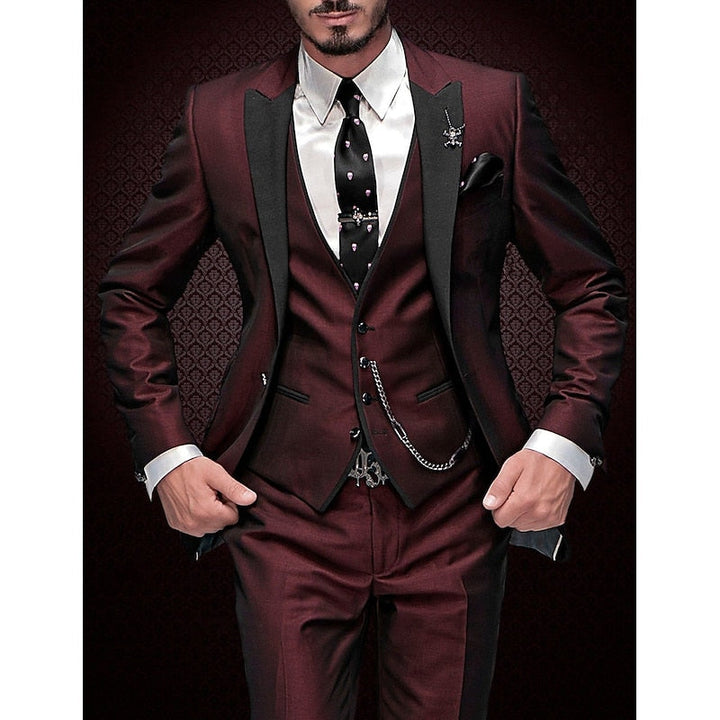 Men's three-piece suit in burgundy with black peak lapels, white shirt and black skull-print tie.