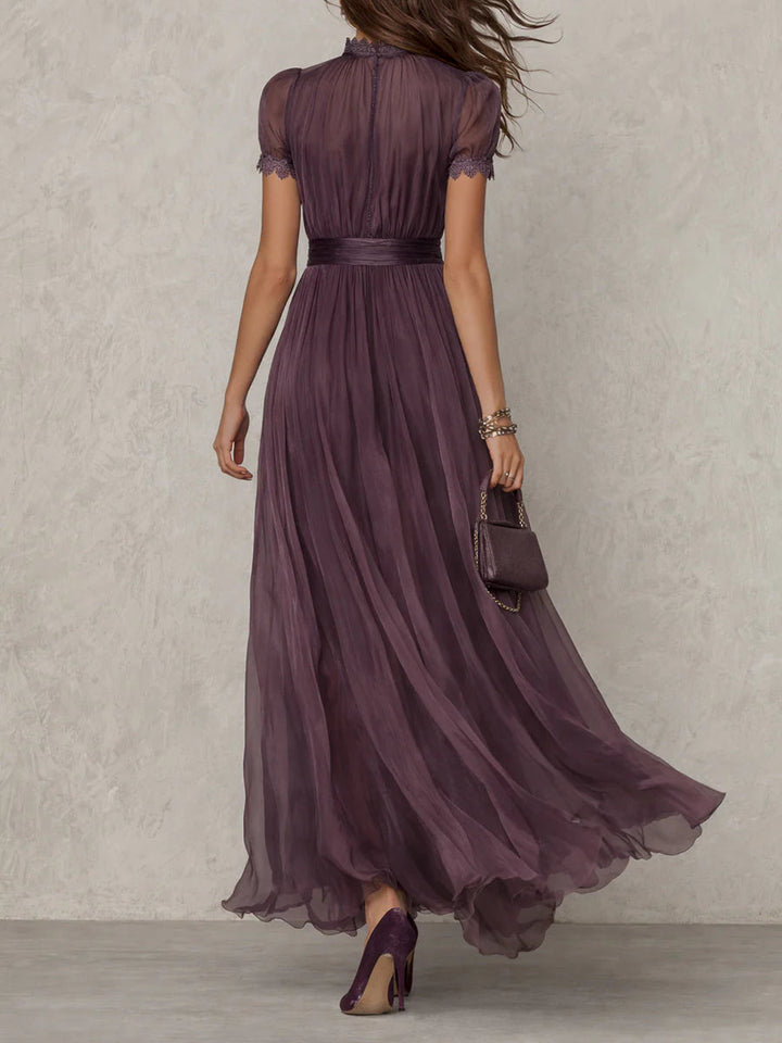 Women's purple maxi dress, back view, with button closure back, gathered waistband, lace-trimmed sleeves, and a flowing sheer skirt.