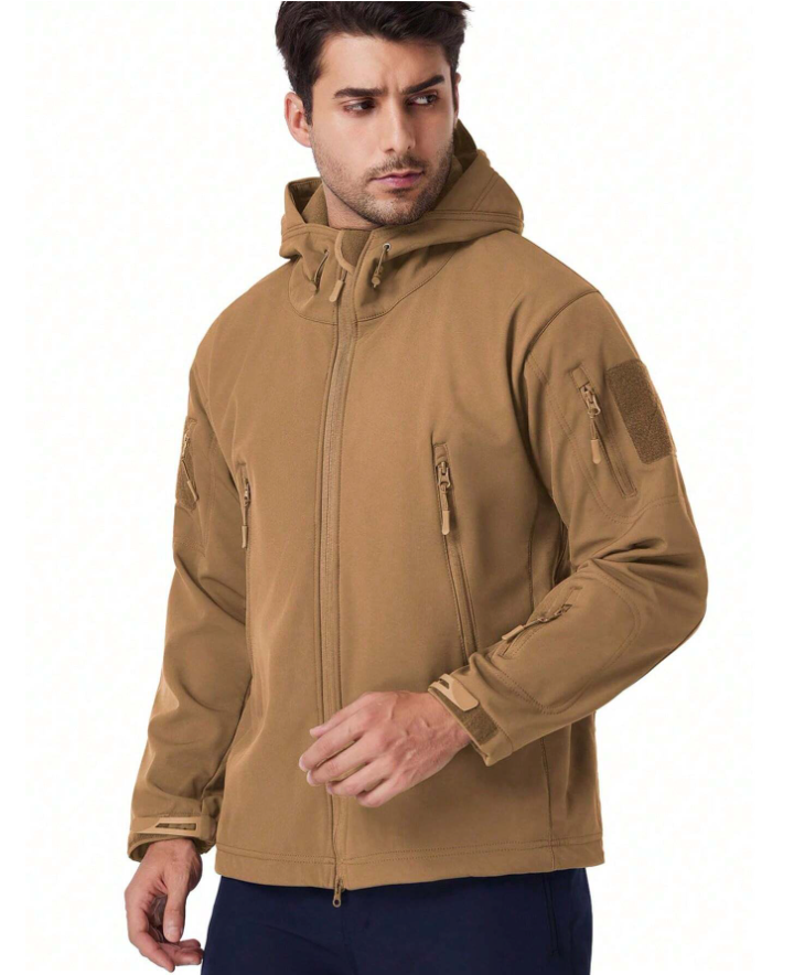 Man wearing the tan hooded jacket, front three-quarter view, looking aside, with chest zip pockets and a sleeve patch. 16