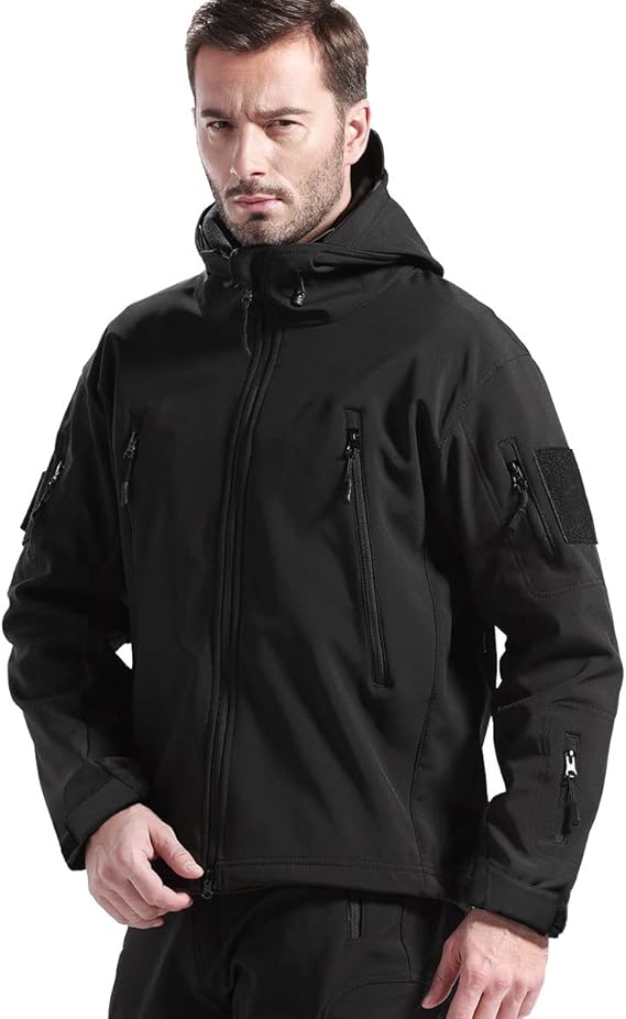 Man wearing the black hooded jacket, front view, zipped up, with chest, sleeve and forearm zip pockets and a sleeve patch. 2