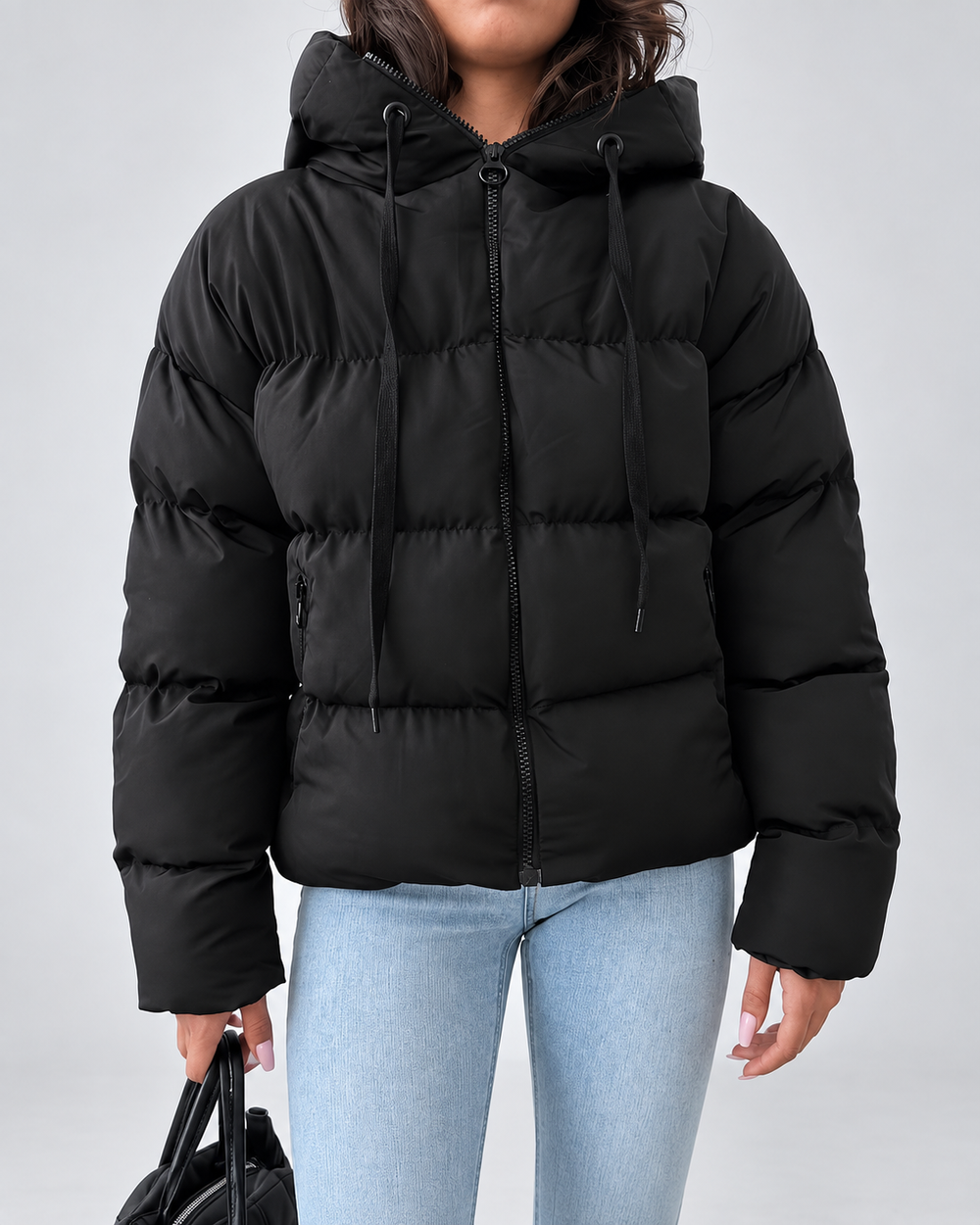 Front view of the black puffer jacket zipped up, with hood drawstrings and zippered side pockets.