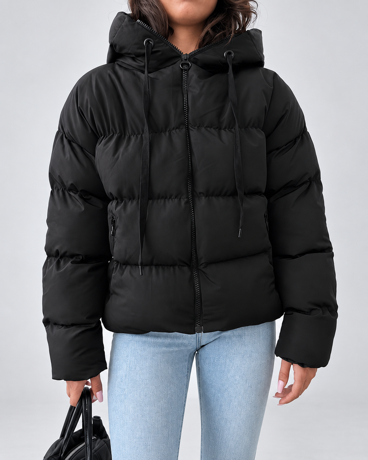 Front view of the black puffer jacket zipped up, with hood drawstrings and zippered side pockets.